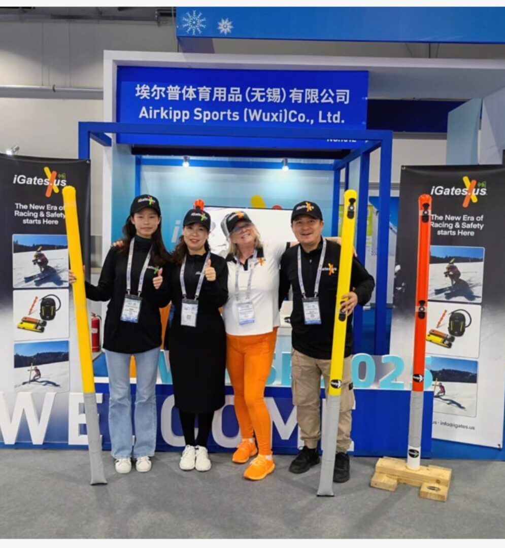Four people posing at an AirSnap Sports exhibition booth.