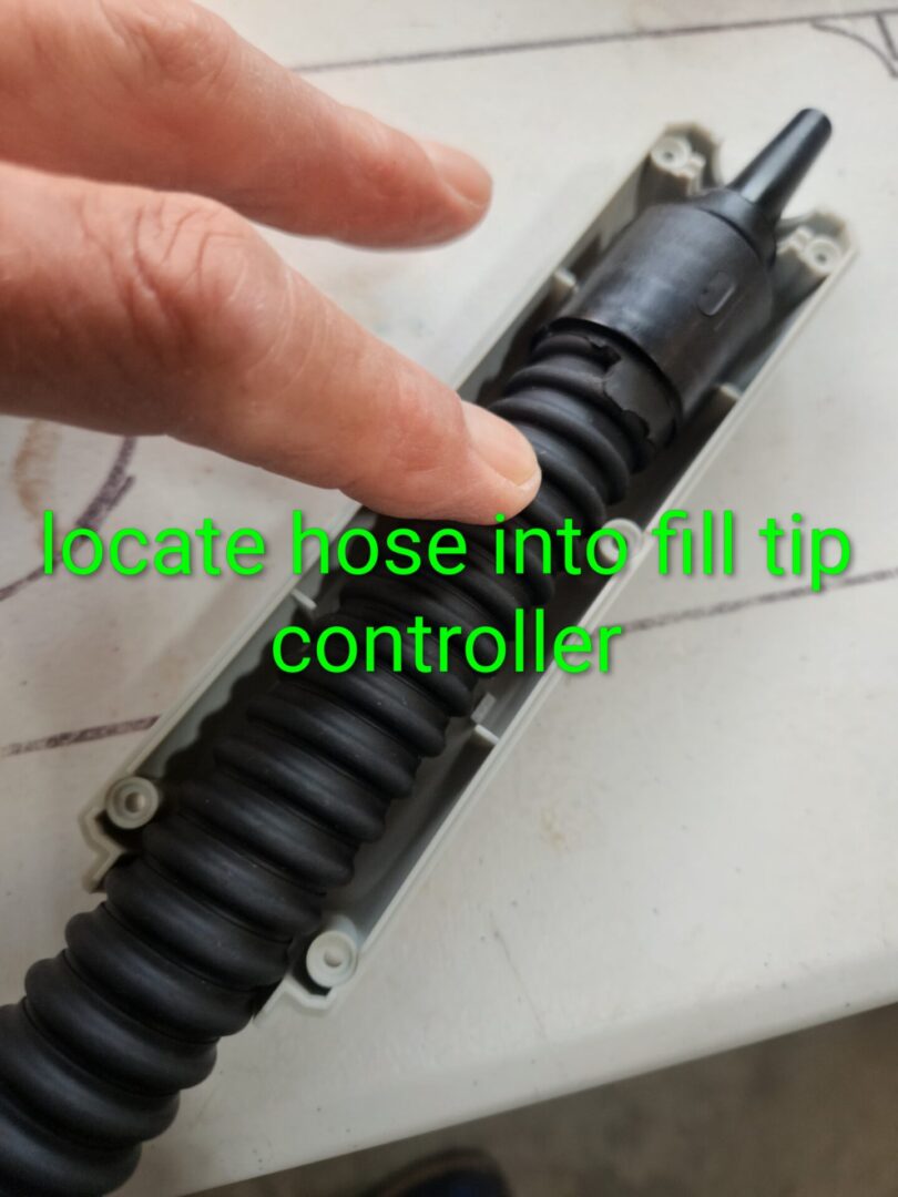 Close-up of a hand guiding a hose into a fill tip controller.