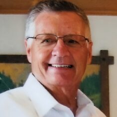 Smiling older man wearing glasses and white shirt
